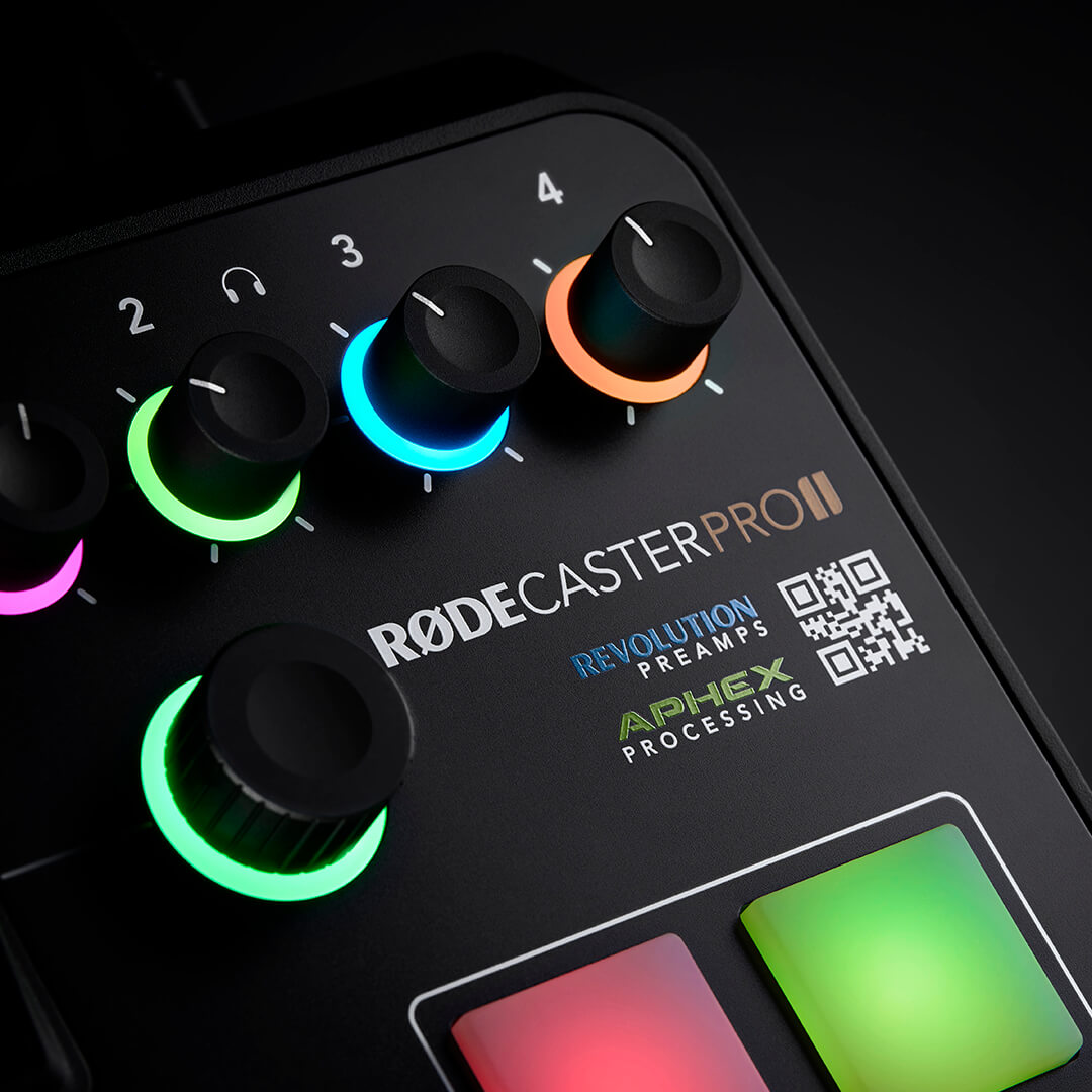 Close-up of the RØDECaster Pro II gain knobs with colour-lit rings, the Revolution Preamps and APHEX Processing badges, and two SMART pads.